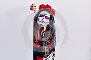 Young woman wearing day of the dead custome holding blank empty banner touching mouth with hand with painful expression because of