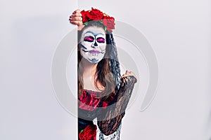 Young woman wearing day of the dead custome holding blank empty banner very happy and excited doing winner gesture with arms