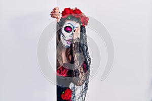 Young woman wearing day of the dead custome holding blank empty banner yawning tired covering half face, eye and mouth with hand