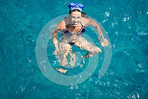 Young woman wearing diving googles swimming and doing snorket at the sea