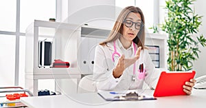 Young woman wearing doctor uniform having teleconsultation at clinic