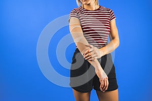 a young woman wearing an elbow support brace over a blue background, trauma concept