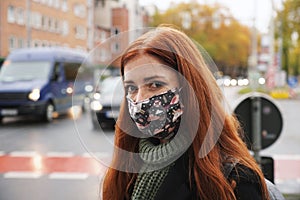 Young woman wearing everyday cloth face mask outdoors in city raffic photo