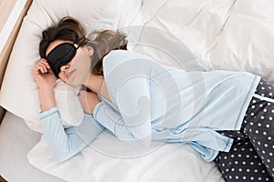 Woman Wearing Eyemask While Sleeping On Bed photo