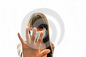 Young woman wearing face mask gesturing to stop