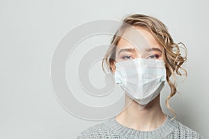 Young woman wearing a face mask on gray background. Flu epidemic and virus protection concept