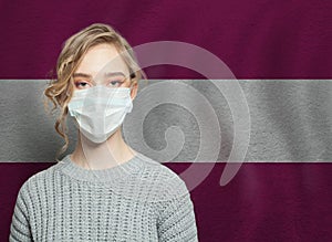 Young woman wearing a face mask with Latvia  flag. Flu epidemic and virus protection concept