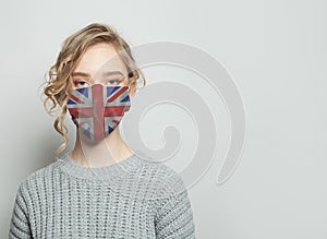 Young woman wearing a face mask with national flag UK flag. Flu epidemic and virus protection concept