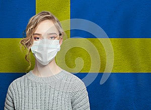 Young woman wearing a face mask with Sweden  flag. Flu epidemic and virus protection concept