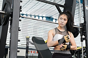 young woman wearing gloves in fitness center. female athlete prepare for training in gym. sporty girl ready for working out in he