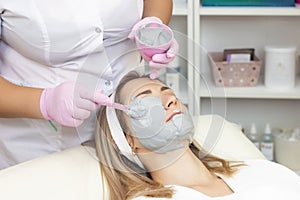 Young woman is wearing a gray alginate mask.