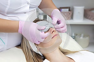 Young woman is wearing a gray alginate mask.