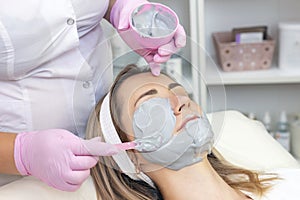 Young woman is wearing a gray alginate mask.