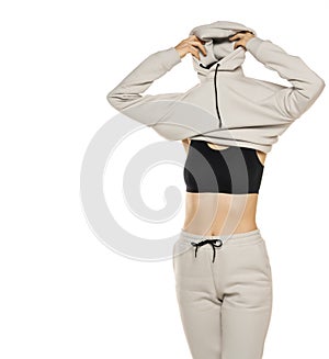 A young woman wearing gray tracksuit and hood against a white background in the studio