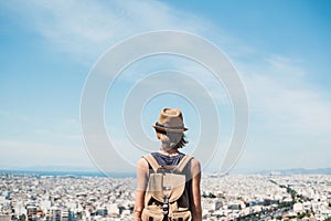 Young woman wearing hat looking at a big city. Traveler girl enjoying vacation. Summer holidays, vacations, travel, concept