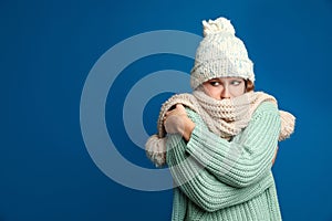 Woman wearing hat and scarf suffering from fever on blue background, space for text. Cold symptoms