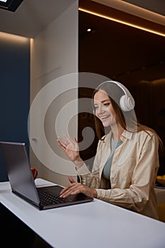 Young woman wearing headphones having meeting on laptop from home