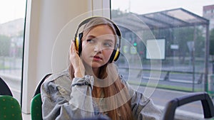 Young woman wearing headphones listening music, funny relax dancing while traveling by bus to city