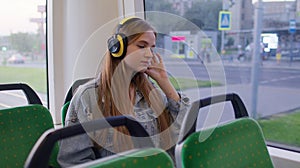 Young woman wearing headphones listening music, funny relax dancing while traveling by bus to city