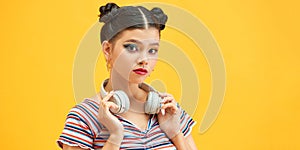 Young woman wearing  headphones on neck over yellow background