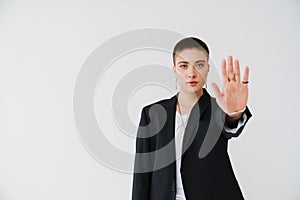 Young woman wearing jacket showing her palm at camera