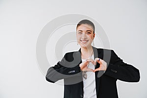 Young woman wearing jacket smiling and showing heart gesture