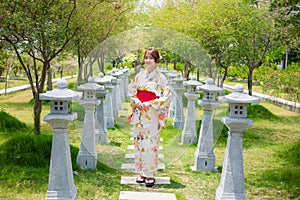 Young woman wearing a Japanese traditional kimono or yukata stand in a garden