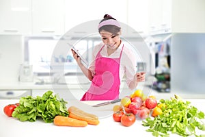 Young woman wearing kitchen apron with tablet