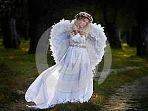 Young woman wearing long white dress and angel wings