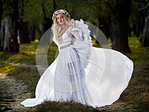 Young woman wearing long white dress and angel wings