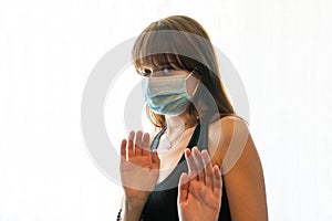 Young woman wearing medical face mask recoils in fear