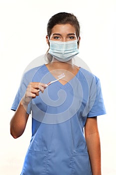 Young Woman Wearing Medical Scrubs and a Surgical Mask and Holding a Toothbrush
