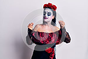 Young woman wearing mexican day of the dead makeup doing money gesture with hands, asking for salary payment, millionaire business