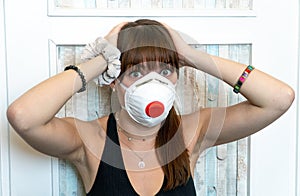 Young woman wearing N95 respirator. Stressed out due to self isolation in times of Coronavirus