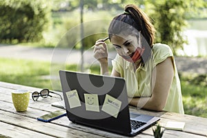 Young woman wearing open protective face mask using laptop outdoors - Pensive female solopreneur working in alternative workspace