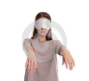 Young woman wearing pajamas and mask in sleepwalking state on white background
