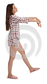 Young woman wearing pajamas and slippers in sleepwalking state on white background