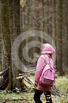 Young woman wearing pink hoodie walking in autumn forest