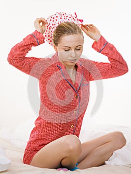 Young woman wearing pink pajamas putting bathing cap