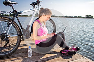 Young woman wearing in pink shirt sitting on the lake bridge using laptop computer