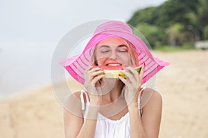 Young woman wearing pink sunhat eating fresh watermelon