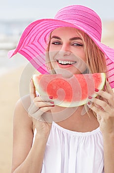 Young woman wearing pink sunhat smiling and eating watermelon