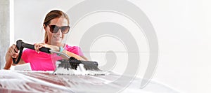 Young woman wearing pink t shirt and sunglasses cleaning her car in self serve carwash, wide banner with space for text right side