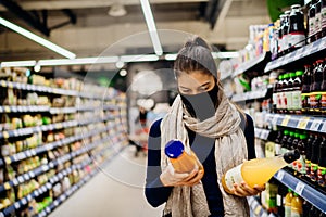 Young woman wearing protective face mask shopping in a supermarket,buying bio food and natural juice.Eating healthy food during