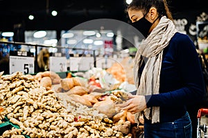 Young woman wearing protective face mask shopping in a supermarket,buying organic food and spices.Eating healthy food during