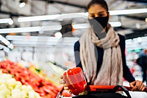 Young woman wearing protective face mask shopping in a supermarket,buying organic produce and ingredients.Eating healthy food