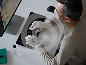 Young woman wearing protective gloves on hands and mask on face working from office or home using laptop on desk.