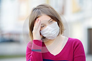 Young woman wearing a protective mask in public place. Safety during COVID-19 outbreak