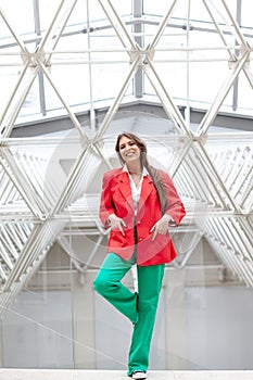 young woman wearing red jacket and green trousers