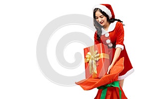 Young woman wearing red santa claus outfit picking up gift box or present from Santa Claus Bag for giving gift isolated on white b